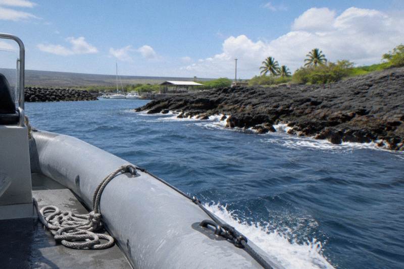 A small inflatable raft cruising along the Kona lava coastline